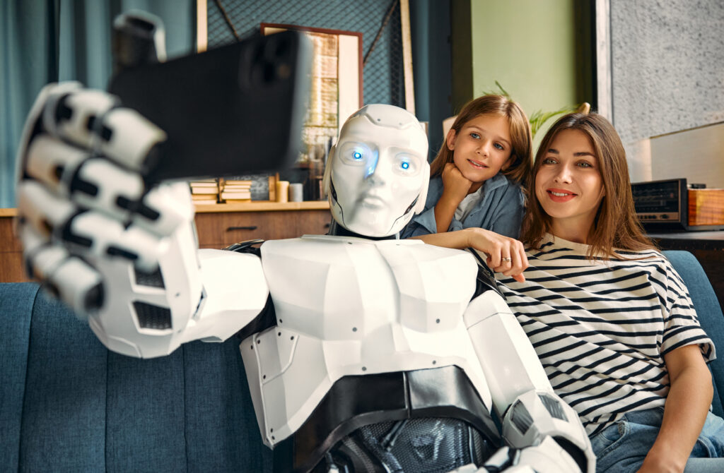 Mom with her daughter and a robot sitting on the sofa in the living room taking a selfie on a smartphone. Living together between humans and artificial intelligence.